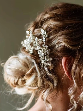 Servizio sposa. Capelli ondulati raccolti in basso con gioiello deecorativo. Acconciatura Io Vanesia.